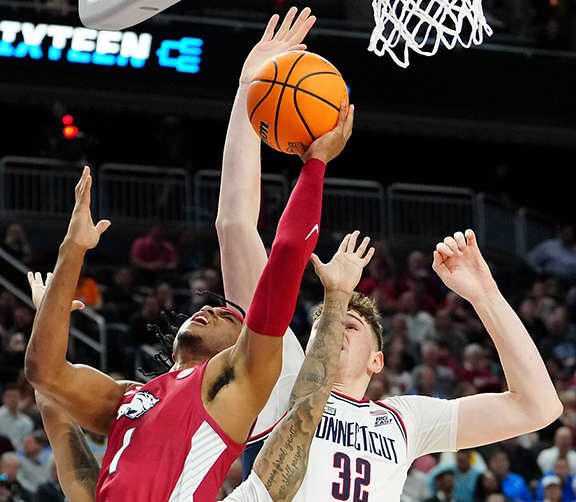 A UConn player blocks the shot of Arkansas guard Ricky Council.